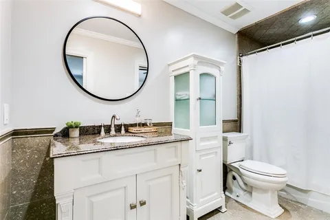 a bathroom with a granite countertop toilet sink and mirror