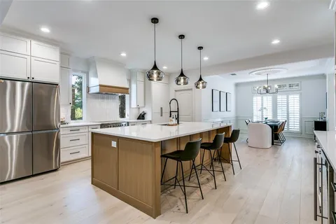 a kitchen with kitchen island granite countertop wooden floor a refrigerator a sink and a stove