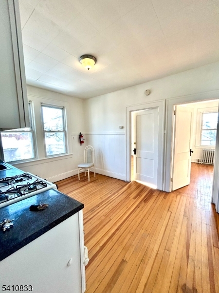 29 Adams Street, Unit 2 Irvington, NJ 07111 - Photo 10 of 14 a kitchen with stainless steel appliances granite countertop a stove a sink dishwasher and a dining table with wooden floor