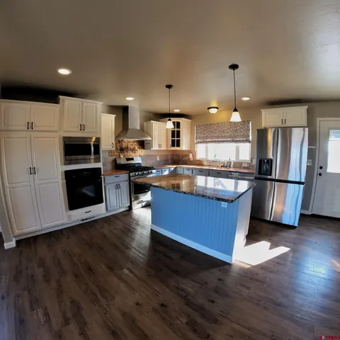 a kitchen with stainless steel appliances granite countertop a refrigerator a stove top oven a sink and dishwasher