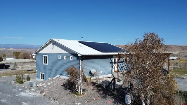 a backyard of a house with table and chairs under an umbrella