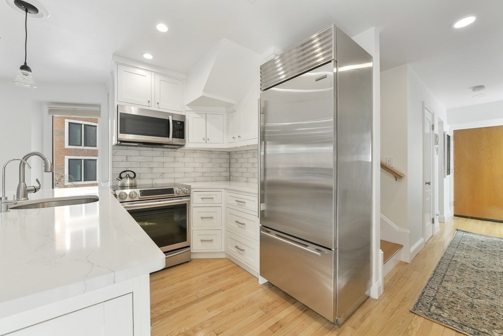 492 Beacon Street, Unit 82 Boston, MA 02115 - Photo 7 of 21 a kitchen with kitchen island granite countertop a refrigerator stove and sink