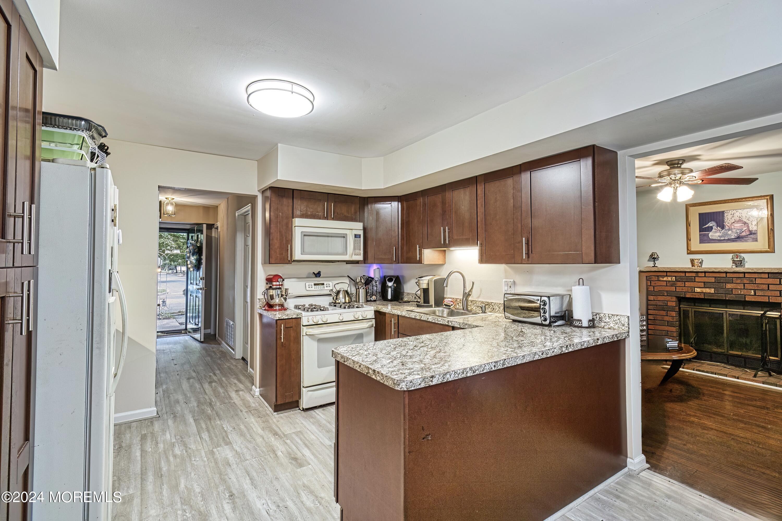 34 Sweetbriar Trail Howell, NJ 07731 - Photo 35 of 53 a kitchen with a stove a sink dishwasher a refrigerator and a dining table with wooden floor