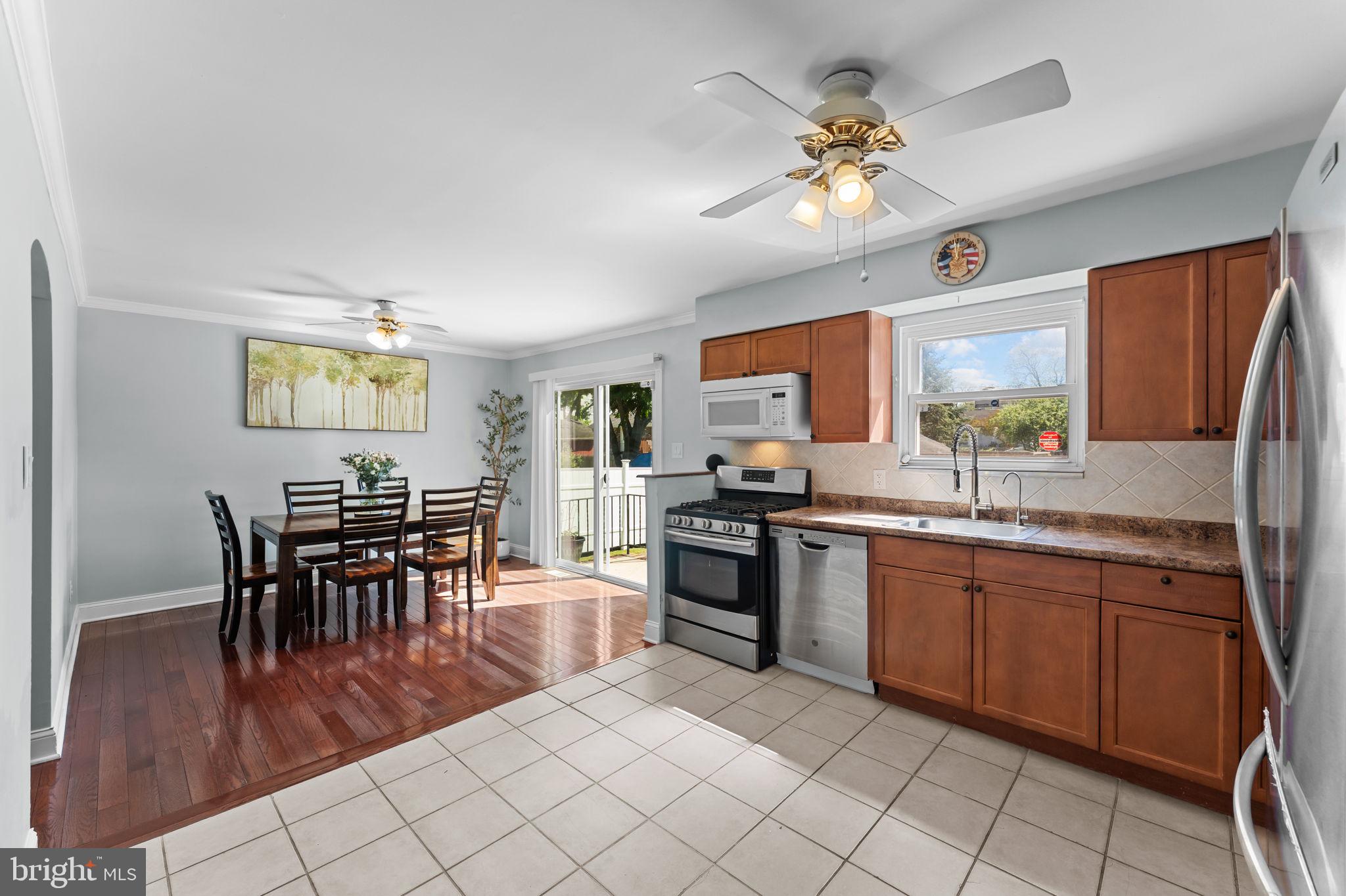 418 Harrison Street Riverside, NJ 08075 - Photo 10 of 29 a open kitchen with stainless steel appliances granite countertop a stove top oven a sink a dining table and chairs with wooden floor