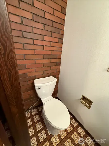 a toilet sitting in a bathroom next to a wooden wall