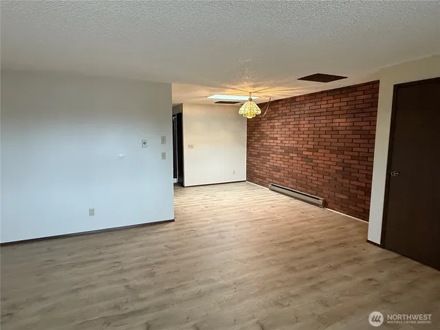 a view of an empty room with wooden floor and stairs