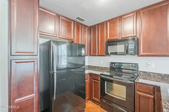 a kitchen with granite countertop stainless steel appliances a refrigerator stove and microwave