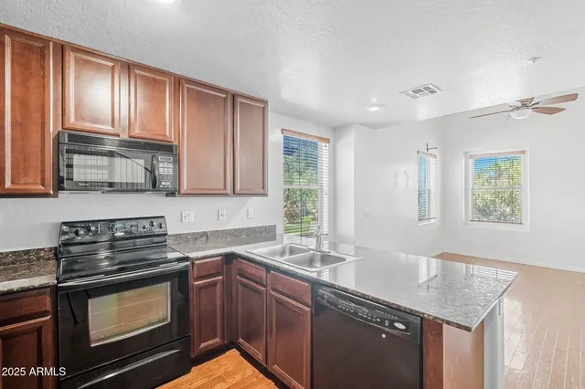 a kitchen with granite countertop stainless steel appliances a stove sink and cabinets
