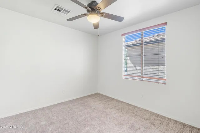 an empty room with a window and a fan