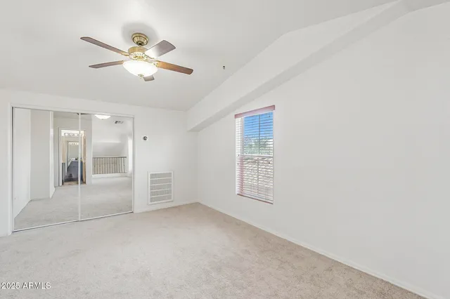 an empty room with windows and fan