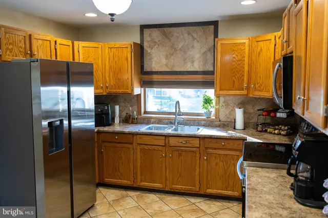 a kitchen with stainless steel appliances granite countertop a refrigerator a sink a stove top oven and a refrigerator