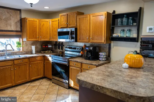 a kitchen with stainless steel appliances granite countertop wooden cabinets a stove top oven a counter space and a window