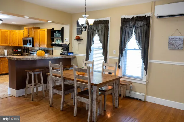 a kitchen with stainless steel appliances a dining table chairs and wooden floor