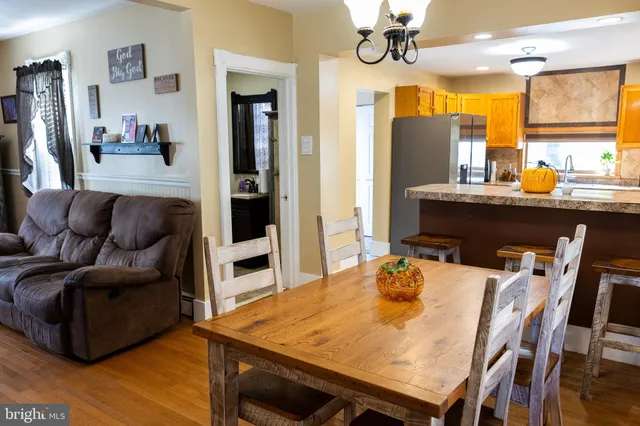 a living room with stainless steel appliances furniture a chandelier and a dining table
