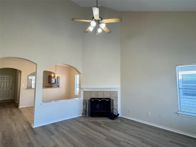 a view of an empty room with wooden floor fireplace and a window