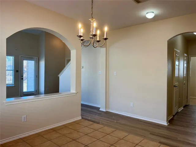 a view of a hallway with wooden floor and chandelier
