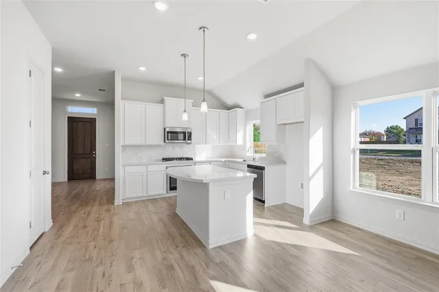 a kitchen with kitchen island a white counter top space wooden floor and a sink