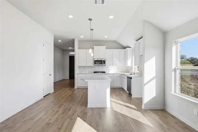 a view of a kitchen with a refrigerator a microwave and a stove top oven
