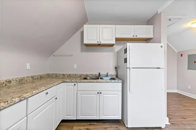 a kitchen with granite countertop a refrigerator sink stove and cabinets