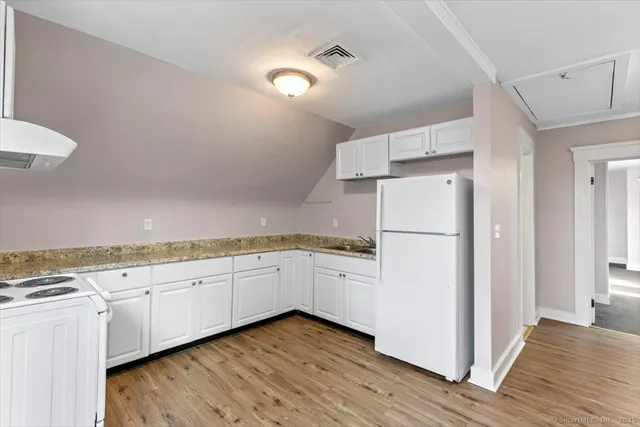 a kitchen with granite countertop white cabinets and white appliances
