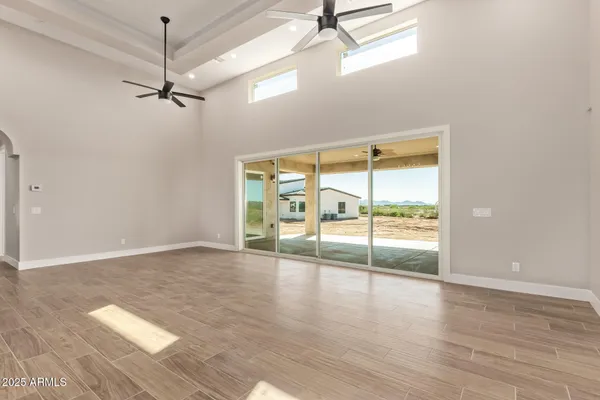 an empty room with wooden floor fan and windows