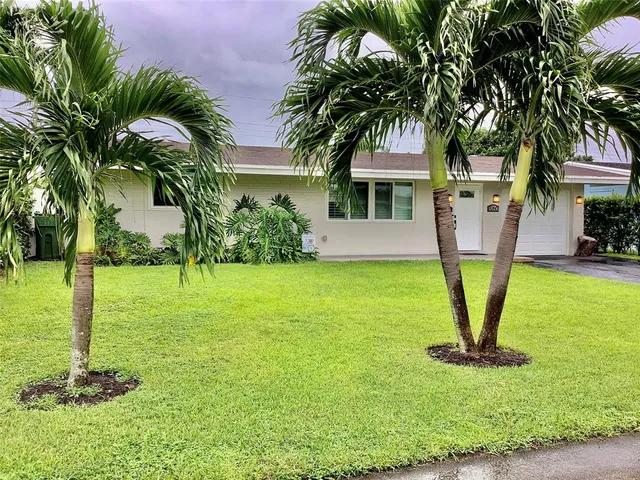 a front view of a house with garden and trees