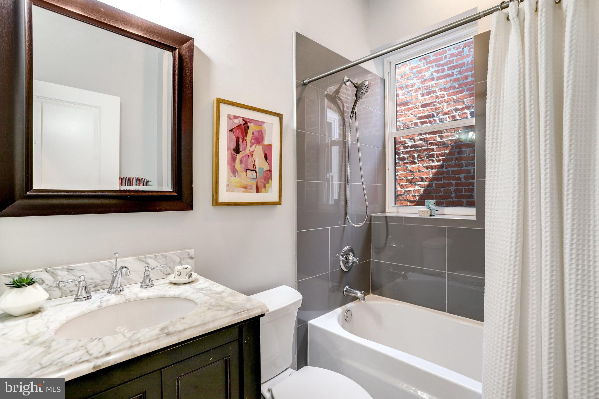 1304 E Street Northeast Washington, DC 20002 - Photo 21 of 42 a bathroom with a granite countertop sink a toilet a shower and a mirror