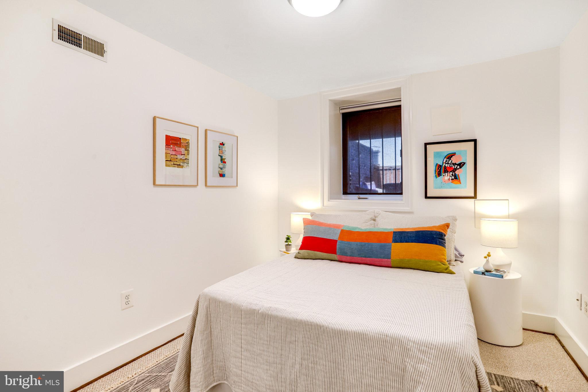 1304 E Street Northeast Washington, DC 20002 - Photo 30 of 42 a bedroom with a bed and a lamp on dresser