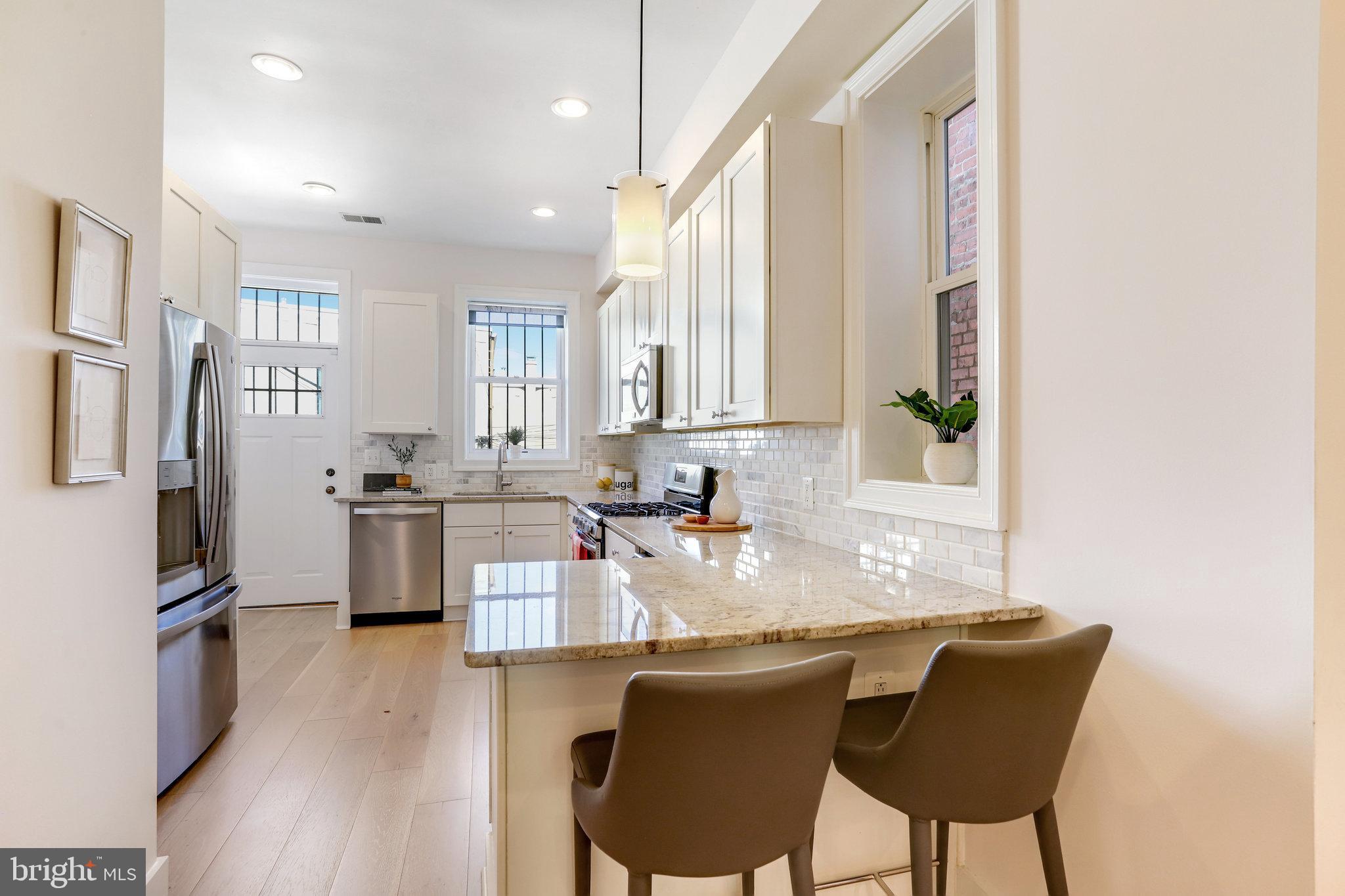1304 E Street Northeast Washington, DC 20002 - Photo 9 of 42 a kitchen with granite countertop furniture cabinets stainless steel appliances and a dining table