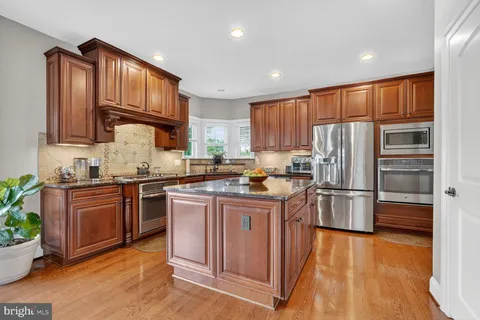 a kitchen with granite countertop a refrigerator stove top oven and sink