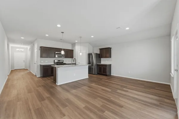 a view of kitchen with kitchen island granite countertop stainless steel appliances refrigerator sink and cabinets