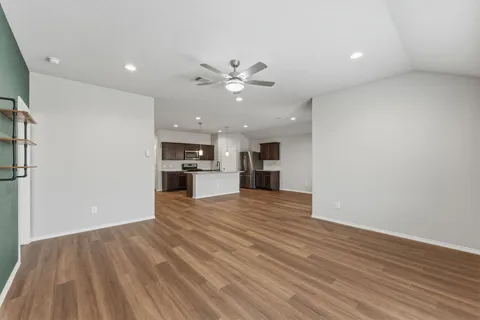 a view of kitchen and empty room with wooden floor