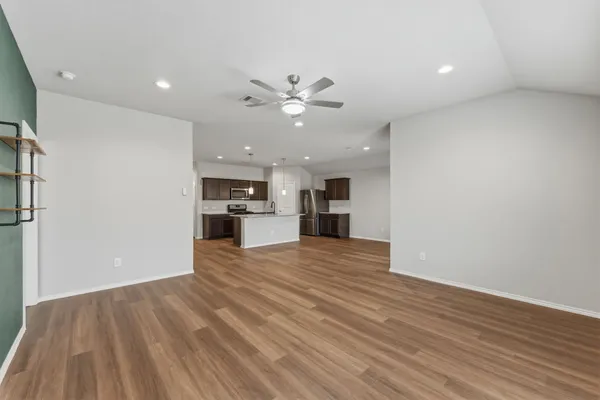 a view of kitchen and empty room with wooden floor