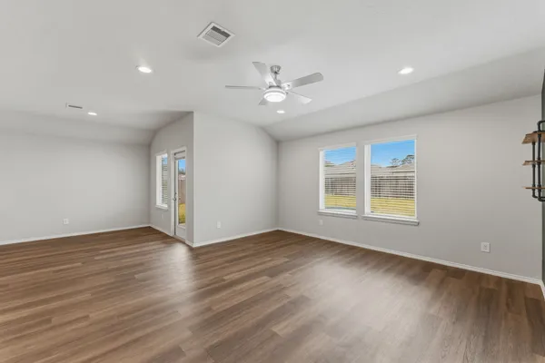 a view of an empty room with wooden floor and a window