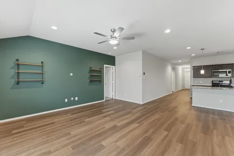 a view of a livingroom with a ceiling fan wooden floor and a ceiling fan