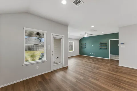 a view of an empty room with wooden floor and a window