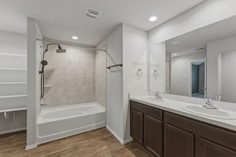 a bathroom with a tub sink double vanity and shower