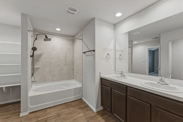 a bathroom with a tub sink double vanity and shower