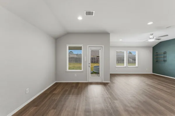 an empty room with wooden floor and windows