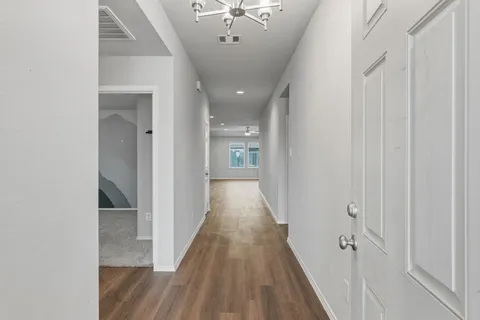 a view of a hallway with wooden floor and a chandelier