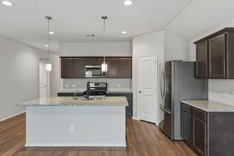 a kitchen with kitchen island granite countertop appliances cabinets a sink and a counter top space