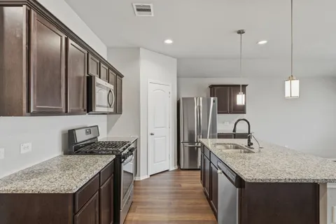 a kitchen with stainless steel appliances granite countertop a kitchen island a stove and a sink