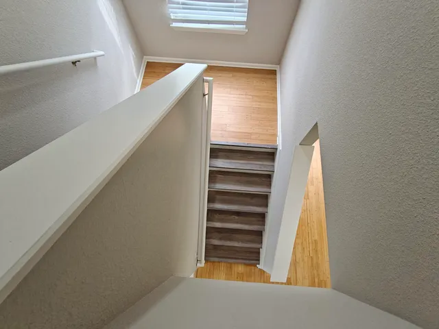 an empty room with wooden floor chandelier and windows