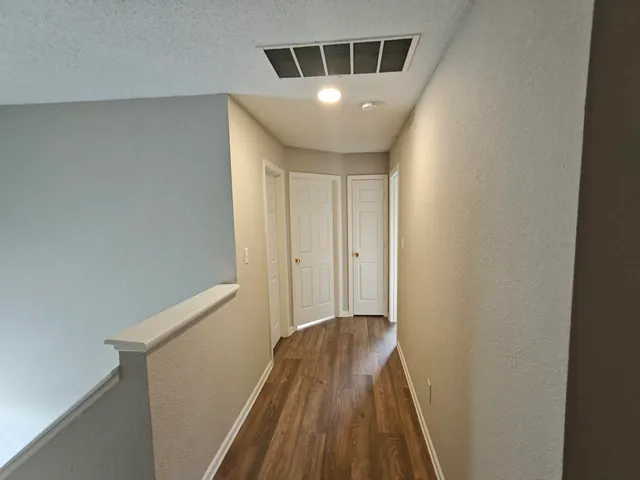 a view of a hallway with wooden floor and staircase