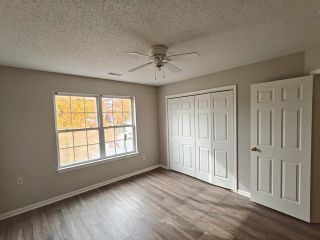 a view of an empty room with a window and wooden floor