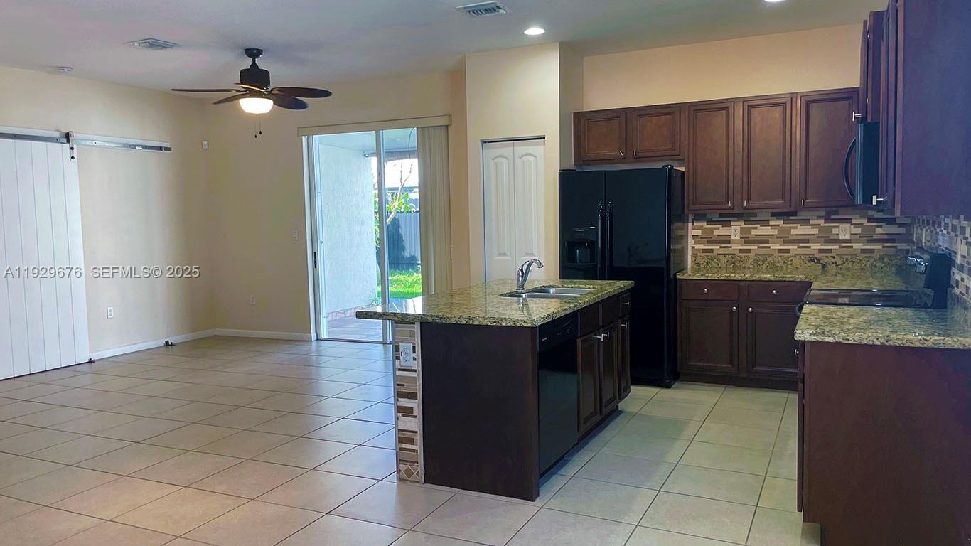 22912 Southwest 115th Court Miami, FL 33170 - Photo 8 of 29 a kitchen with kitchen island granite countertop a refrigerator and a stove