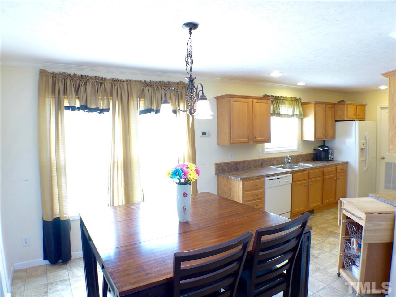 1955 Holly Grove Road Benson, NC 27504 - Photo 6 of 25 a kitchen with granite countertop a table chairs a sink dishwasher window and cabinets