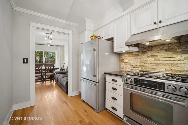 a kitchen with granite countertop a refrigerator stove and wooden floor