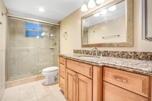 a bathroom with a granite countertop sink a toilet and a mirror