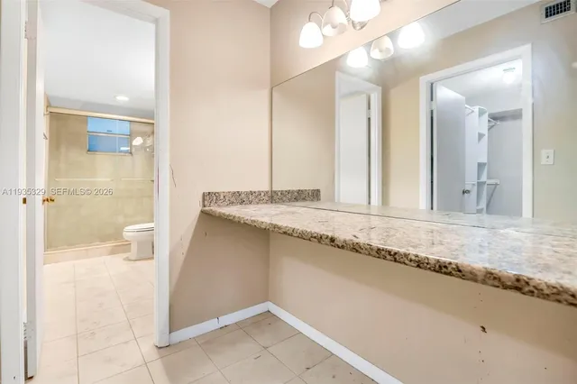 a bathroom with a granite countertop sink and a mirror
